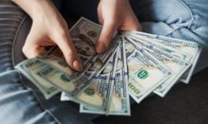 person counting stack of hundred dollar bills